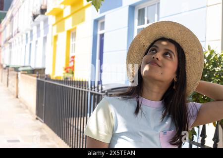 Jeune femme souriante en chapeau de soleil debout dans la rue Banque D'Images