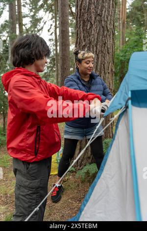 Mère et fils installant une tente dans la forêt Banque D'Images