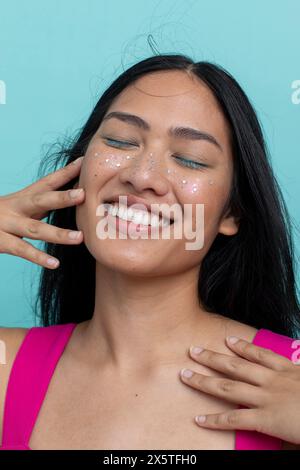 Jeune femme souriante avec les cheveux longs noirs et les yeux fermés Banque D'Images