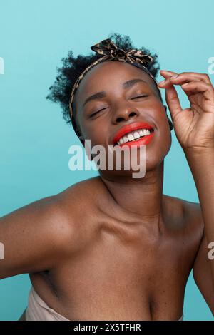 Femme souriante avec les yeux fermés, portant du rouge à lèvres rouge Banque D'Images