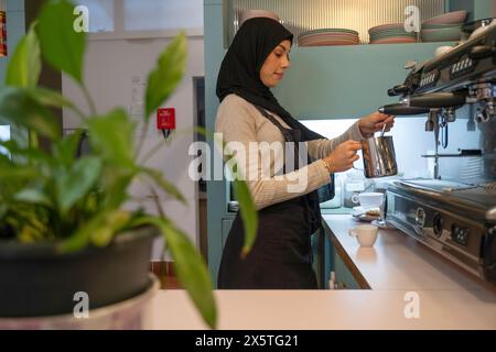 Jeune femme en hijab faisant du café au café Banque D'Images