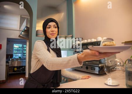 Jeune femme en hijab travaillant dans un café Banque D'Images