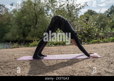 Femme en position de chien face vers le bas dans le parc Banque D'Images