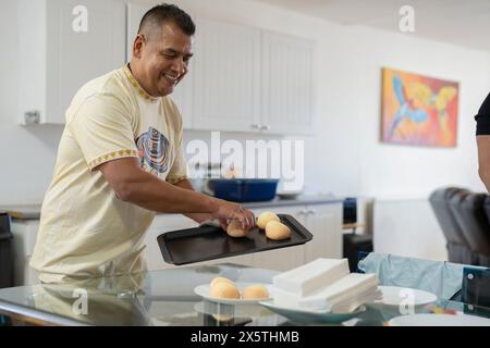 Homme tenant un plateau de petits pains fraîchement cuits Banque D'Images