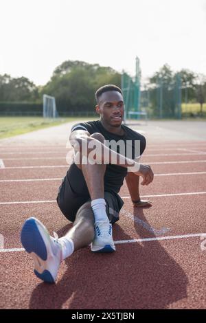 Athlète étirant les jambes avant de s'entraîner sur une piste de sport Banque D'Images