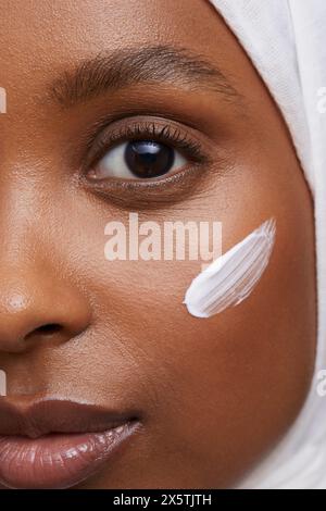 Portrait studio d'une jeune femme en hijab blanc appliquant la crème pour le visage Banque D'Images