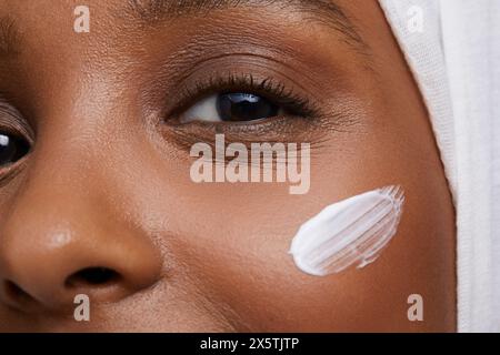 Portrait studio d'une jeune femme en hijab blanc appliquant la crème pour le visage Banque D'Images