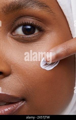 Photo studio d'une jeune femme en hijab blanc appliquant de la crème pour le visage Banque D'Images