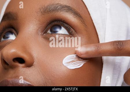 Photo studio d'une jeune femme en hijab blanc appliquant de la crème pour le visage Banque D'Images