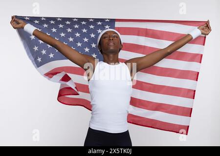 Portrait de studio de femme athlétique dans des vêtements de sport tenant le drapeau américain Banque D'Images