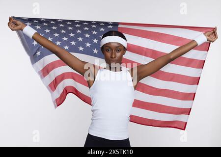 Portrait de studio de femme athlétique dans des vêtements de sport tenant le drapeau américain Banque D'Images