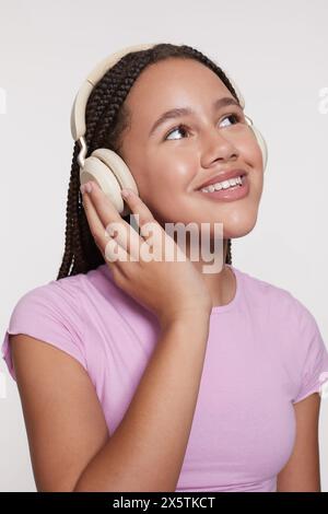 Portrait studio de fille souriante avec écouteurs et yeux fermés Banque D'Images