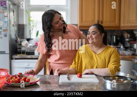 Portrait d'une mère avec une fille trisomique du syndrome de Down préparant la nourriture en cuisine Banque D'Images