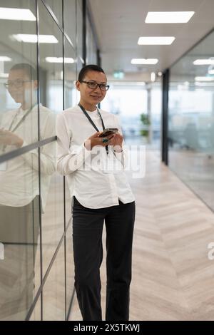 Employé de bureau non binaire debout dans le couloir Banque D'Images