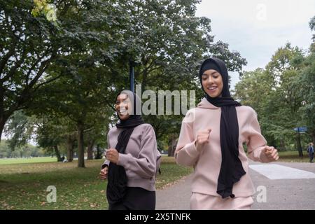 Deux femmes souriantes en hijabs jogging dans le parc Banque D'Images