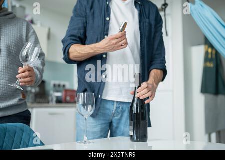 Couple masculin ouvrant du vin rouge à la maison Banque D'Images