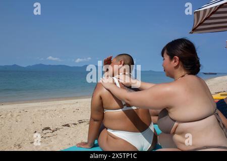 Femme appliquant de la crème solaire à des amis de retour sur la plage Banque D'Images