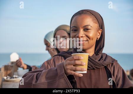 Portrait de femme musulmane buvant du café avec des amis dans le café trottoir Banque D'Images