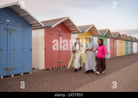 Amis musulmans joyeux marchant à côté des cabanes de plage Banque D'Images