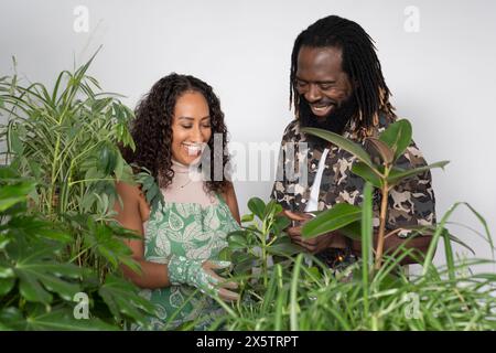 Portrait studio de couple souriant avec des plantes en pot Banque D'Images