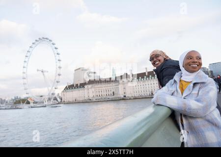 Royaume-Uni, Londres, touristes femmes dans les hijabs regardant le London Eye sur la Tamise Banque D'Images