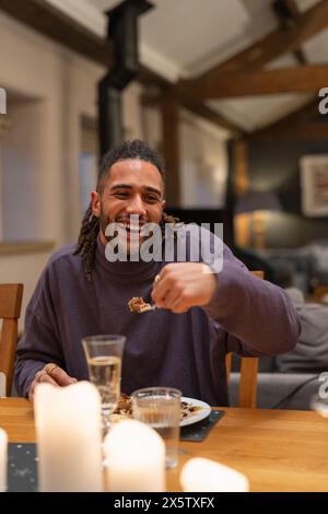 L'homme souriant mange à table Banque D'Images