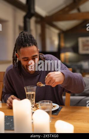 L'homme souriant mange à table Banque D'Images