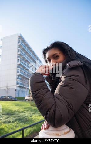 Portrait d'une femme en pardessus appuyée sur un poteau Banque D'Images