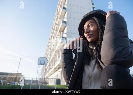 Portrait de femme souriante en pardessus noir avec capuche à l'extérieur Banque D'Images