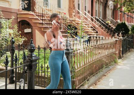 États-Unis, New York City, femme élégante prenant sur le téléphone intelligent dans le quartier résidentiel Banque D'Images