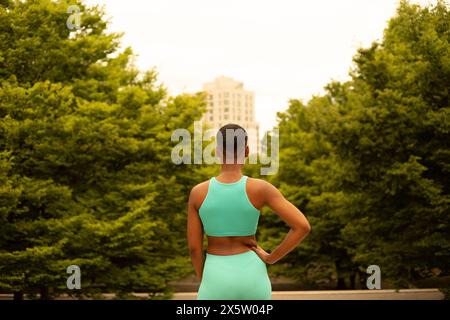 Vue arrière de la femme athlète dans des vêtements de sport debout dans le parc Banque D'Images