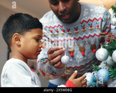 Père et fils decorating Christmas Tree Banque D'Images