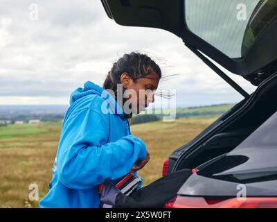 Femme regardant à l'intérieur du coffre de voiture Banque D'Images
