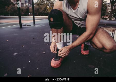 États-Unis, Pennsylvanie, Philadelphie, section basse de l'homme attachant chaussure de sport à l'extérieur Banque D'Images