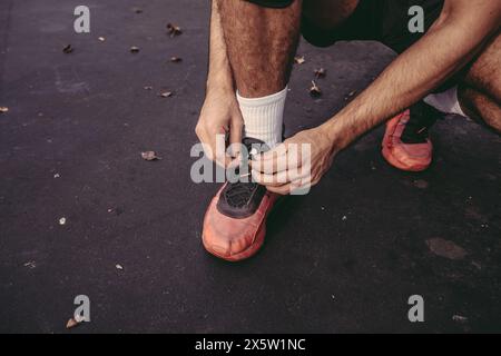 États-Unis, Pennsylvanie, Philadelphie, section basse de l'homme attachant chaussure de sport à l'extérieur Banque D'Images