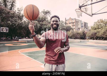 États-Unis, Pennsylvanie, Philadelphie, homme souriant faisant tourner la balle de basket sur le bout des doigts Banque D'Images