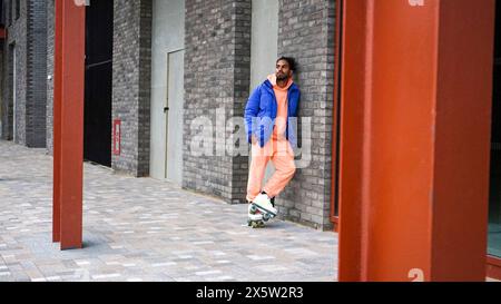 Jeune homme portant une veste bleue et des patins à roulettes Banque D'Images