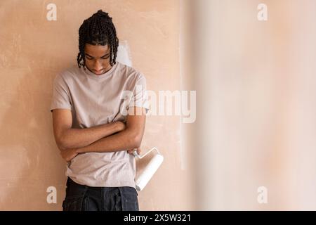 Adolescent avec rouleau à peinture dans la maison Banque D'Images