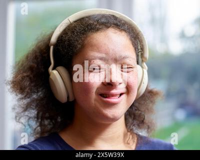 Fille souriante avec syndrome de Down avec écouteurs Banque D'Images