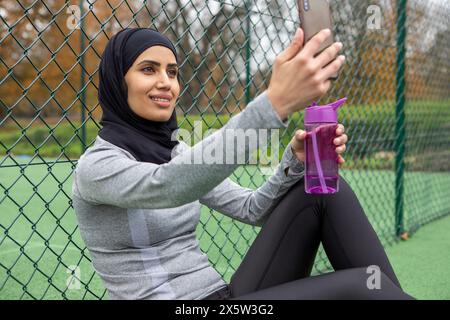 Femme en hijab prenant selfie sur un terrain de basket-ball Banque D'Images