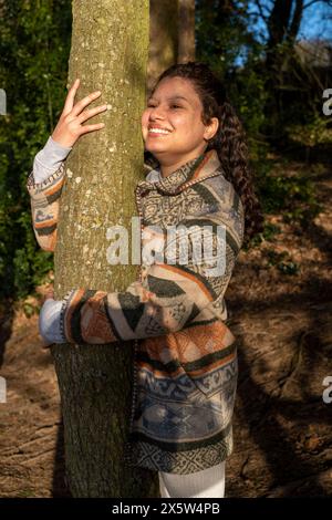 Jeune femme souriante embrassant l'arbre Banque D'Images