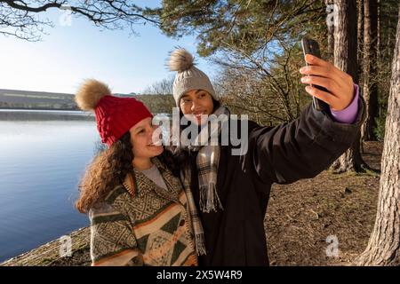 Amies féminines prenant selfie au lac Banque D'Images