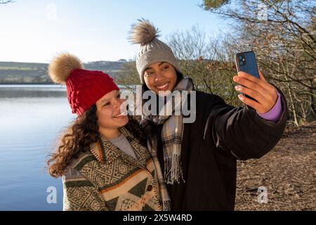 Amies féminines prenant selfie au lac Banque D'Images