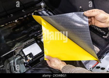 Travailleur de service automobile installant un matériau de mousse insonorisant sur la garniture de porte de voiture de l'intérieur, accordant le son de la voiture ou installant l'isolation phonique. Processus de c Banque D'Images