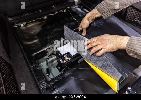 Travailleur de service automobile installant un matériau de mousse insonorisant sur la garniture de porte de voiture de l'intérieur, accordant le son de la voiture ou installant l'isolation phonique. Processus de c Banque D'Images