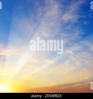 Coucher de soleil lumineux sur le ciel bleu. Les rayons du soleil brillent à travers les nuages. Banque D'Images