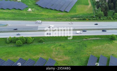 Vol de drone sur une autoroute allemande avec beaucoup de trafic et de grands panneaux solaires à côté de la route Banque D'Images