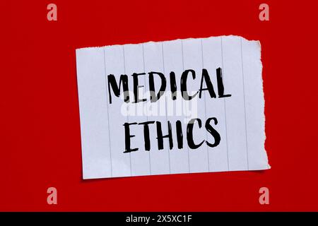 Mots d'éthique médicale écrits sur papier déchiré avec fond rouge. Symbole conceptuel de l'éthique médicale. Copier l'espace. Banque D'Images