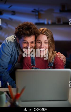 Vertical excité jeune couple caucasien adulte regardant un ordinateur portable surpris de célébrer le succès. Banque D'Images