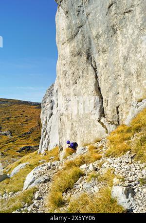 Randonnée dans le parc national de Durmitor, Monténégro : un touriste photographié de loin descend le long d’un sentier de montagne situé près d’une falaise pittoresque Banque D'Images